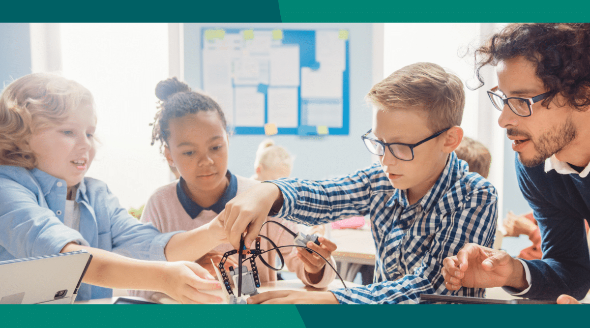 A group of students working together in class with their teacher next to them.