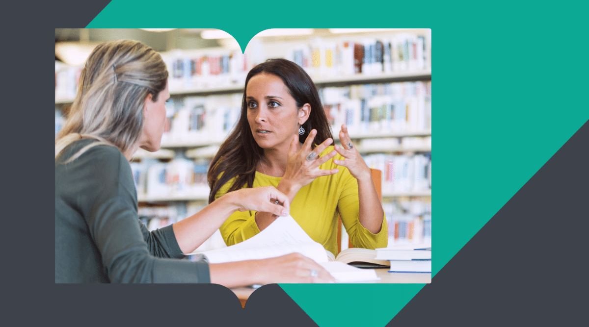 effective-communication-strategies-schools Two women in a library engaged in an intense discussion, with books and notes in front of them, representing communication challenges and strategies in an educational setting.