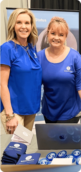 Two employees of SchoolStatus in blue shirts posing for a photo.