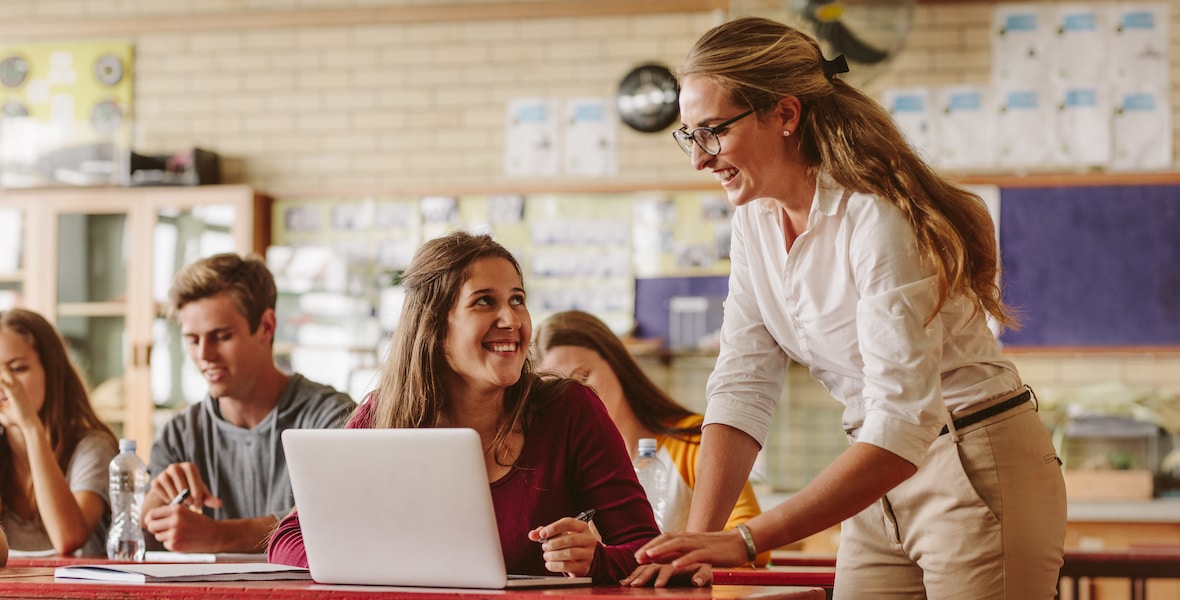 Woman high school professor helping student in class High school professor helping a student with her work.