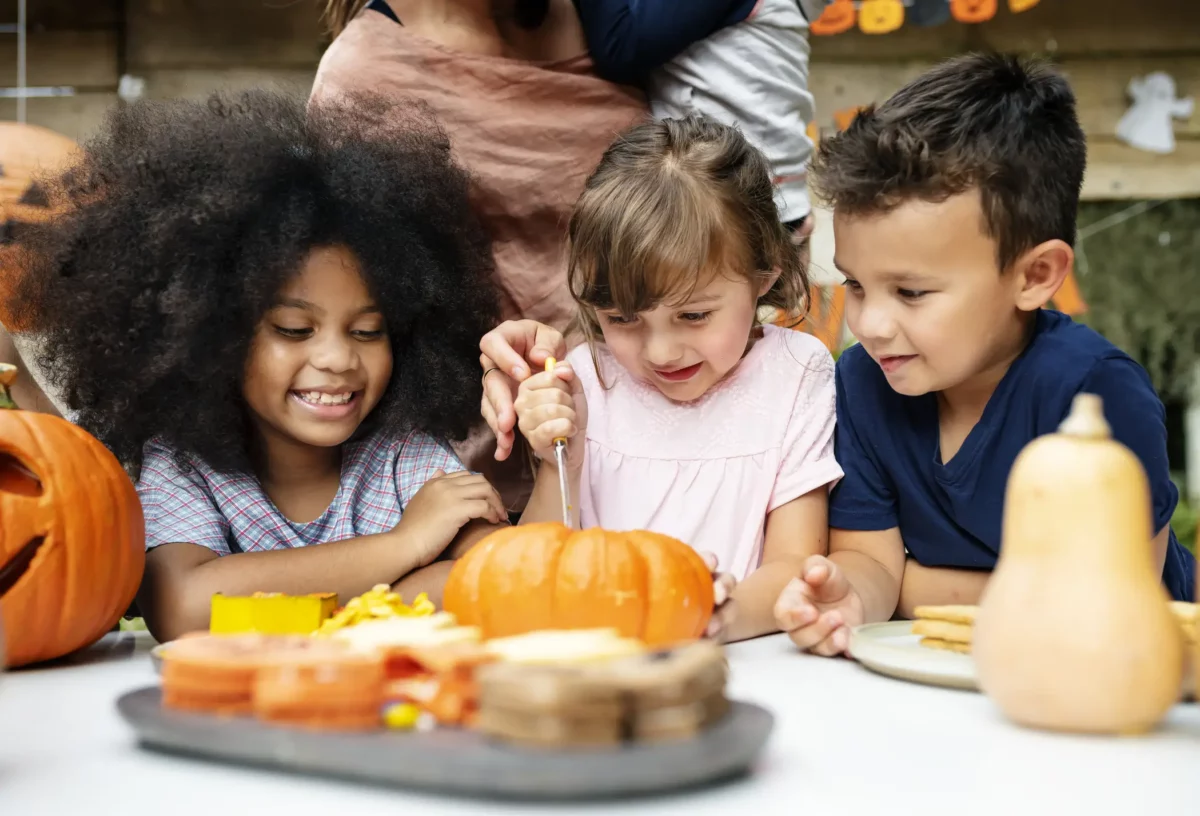 Three kids carving a pumpkin.